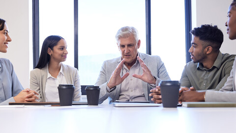 Mentor and mentees sitting at a table discussing project