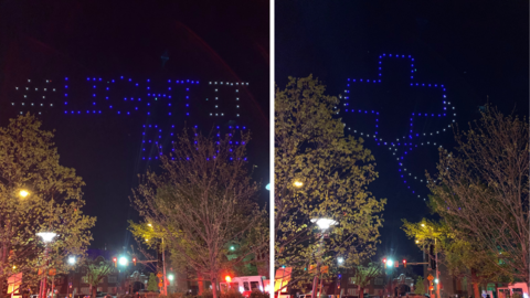 "light it blue" written in the sky with drones through the trees