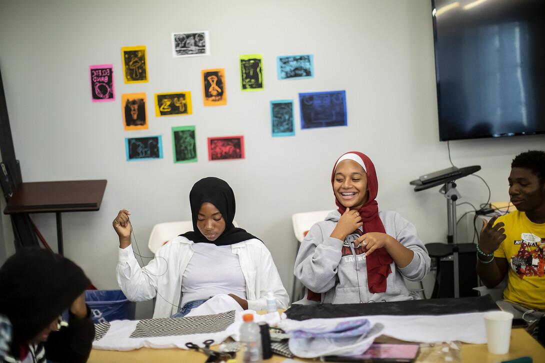 Photo of students sewing with fabric in front of them