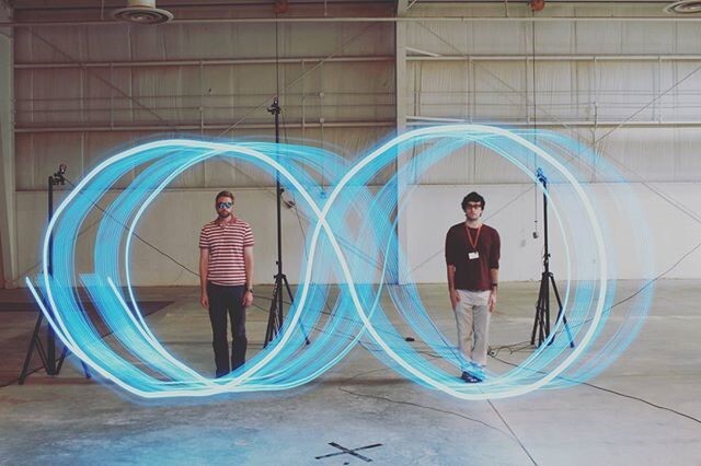 Two men standing in an lighted infinity symbol